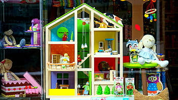 A vibrant dollhouse and stuffed toys displayed in a toy store window, perfect for children's play. HD wallpaper