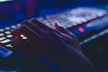 A hand typing on a glowing keyboard in dim lighting, perfect for tech themes. HD wallpaper