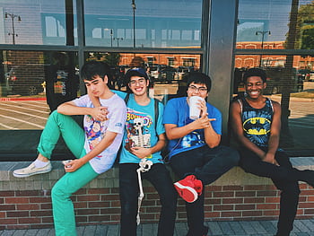 Group of teenage friends sitting outdoors, smiling and having fun together. HD wallpaper