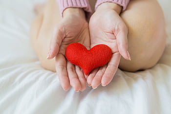 Soft focus on hands holding a red heart, symbolizing wellness and care in a serene setting. HD wallpaper