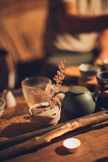 Warm and inviting traditional tea setup with candlelit ambiance, highlighting ceramic tea cups and teapot. HD phone wallpaper
