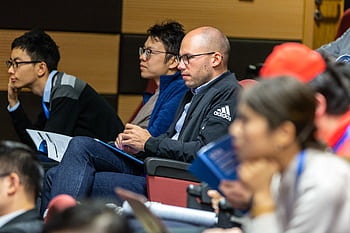 A diverse group of adults attentively listening to a lecture in an indoor conference setting. HD wallpaper