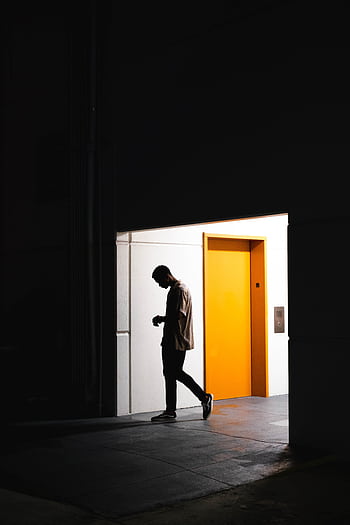 A man walking past a bright yellow elevator door in a minimal urban setting in Orlando, FL. HD phone wallpaper