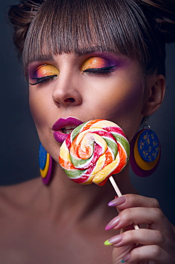 Close-up portrait of a woman with bold colorful makeup and a lollipop. HD phone wallpaper