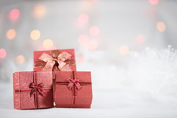 Elegant red gift boxes with ribbons and bows, set against a festive bokeh backdrop. HD wallpaper