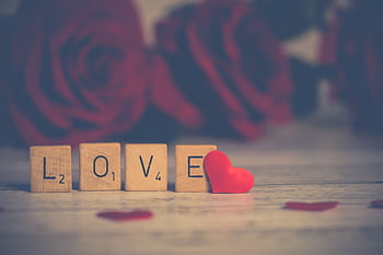 Scrabble tiles spelling 'LOVE' with red roses, perfect for Valentine's Day. HD wallpaper
