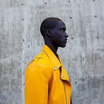 A fashion-forward portrait of a man in a vibrant yellow jacket against a concrete backdrop. HD phone wallpaper