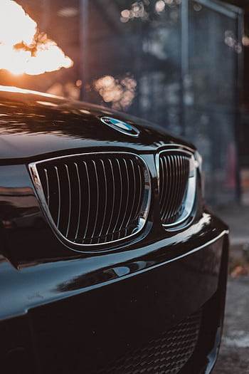 Stylish luxury car grille in focus with sunset reflections, showcasing automotive elegance. HD phone wallpaper