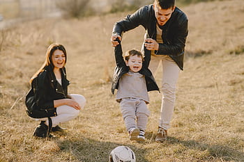 Family enjoying playful soccer game outdoors, capturing joyful moments. HD wallpaper