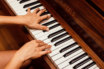 Musician's hands playing wooden piano keys in a high contrast , capturing musical expression. HD wallpaper