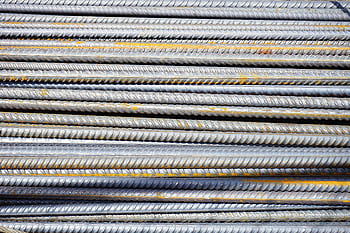 Close-up of stacked rusty steel reinforcing bars used in construction. HD wallpaper