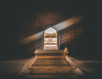 Beautiful tomb interior with a golden sarcophagus, illuminated by sunlight through an ornate archway. HD wallpaper