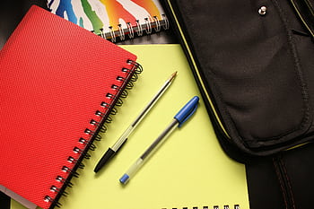 A close-up view of colorful notebooks and pens, perfect for educational themes. HD wallpaper