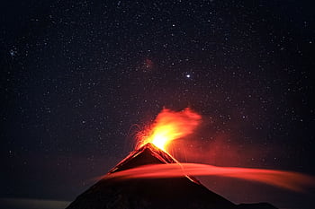 A dramatic volcano eruption in Guatemala beneath a star-filled night sky, showcasing nature's power. HD wallpaper