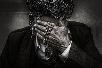 Black and white portrait of an elderly man covering his face with a traditional headscarf and prayer beads. HD wallpaper