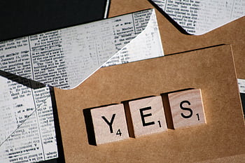 Close-up of Scrabble letters spelling YES on a vintage-style envelope for invitation or message. HD wallpaper