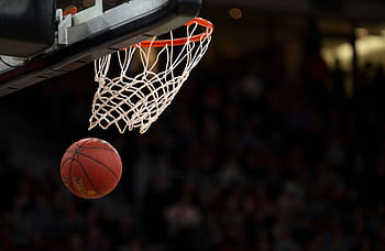 A basketball going through the hoop during a fast-paced game, capturing the excitement of the sport. HD wallpaper
