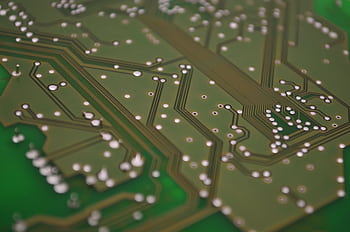 Detailed view of a printed circuit board showcasing intricate chip connections and pathways. HD wallpaper