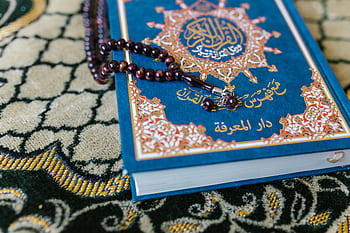 A Quran with prayer beads on a decorative carpet, symbolizing Islamic spirituality. HD wallpaper