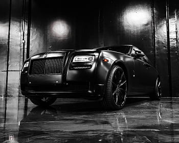 Sleek black luxury car displayed in a dramatic showroom environment. HD wallpaper