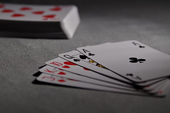Detailed view of playing cards displaying a winning poker hand in a dimly lit scene. HD wallpaper