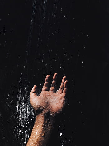 A dramatic of a hand catching water against a dark background, evoking a moody atmosphere. HD phone wallpaper