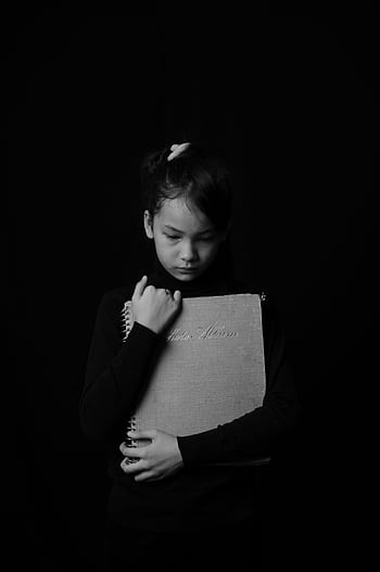 A monochrome of a child holding a book, expressing deep emotion. HD phone wallpaper