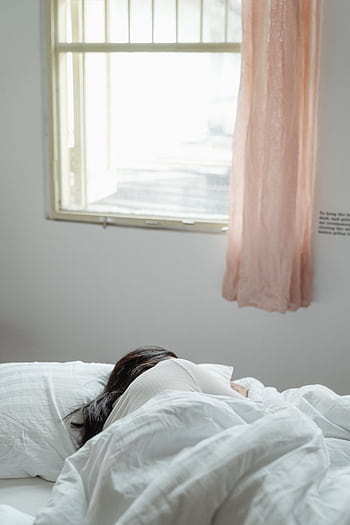 A woman peacefully sleeping in a sunlit bedroom with soft bedding and curtains. HD phone wallpaper