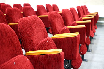 Empty auditorium rows of plush red velvet theater seats. Perfect for cinema and lecture hall themes. HD wallpaper