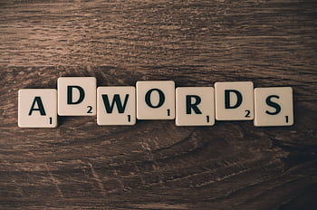Scrabble tiles spelling 'AdWords' on a wooden surface, symbolizing digital marketing concepts. HD wallpaper