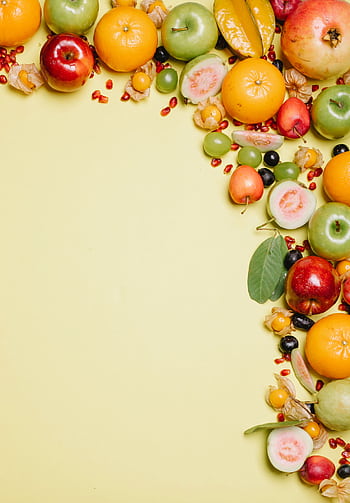 Fresh and colorful assortment of tropical and exotic fruits arranged on a bright yellow background. HD phone wallpaper