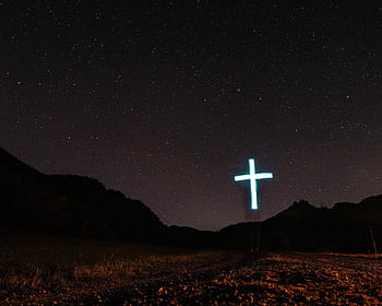 A scenic night view with a glowing cross under a starry sky, evoking spirituality. HD wallpaper