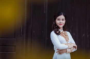 Portrait of an elegant Asian woman wearing a traditional Ao Dai dress indoors. HD wallpaper