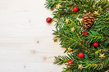 Christmas garland with pine cones and ornaments on wooden background, perfect for holiday decor. HD wallpaper