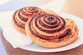 A close-up view of two freshly baked cinnamon rolls served on a white plate. HD wallpaper
