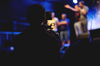 A cameraman films a live concert performance, capturing the dynamic stage action. HD wallpaper