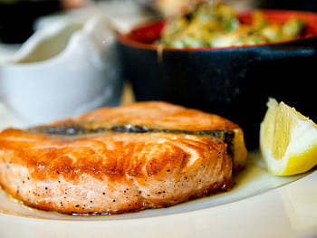Delicious pan-seared salmon steak garnished with a lemon slice, showcasing a perfect dining experience. HD wallpaper