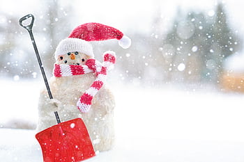 Charming snowman wearing a Santa hat and scarf with a red shovel in a snowy setting. HD wallpaper