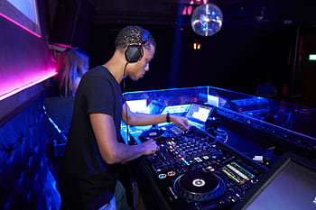 DJ mixes music at a vibrant nightclub with disco lights and an enthusiastic crowd. HD wallpaper