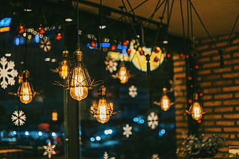 Warm and festive cafe ambiance with hanging bulbs and snowflake decorations. HD wallpaper