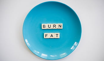 A conceptual featuring the words 'Burn Fat' on a blue plate, symbolizing weight loss. HD wallpaper