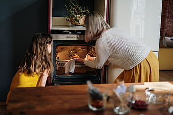 A mother and daughter baking a cake in a cozy kitchen setting, enhancing family time. HD wallpaper