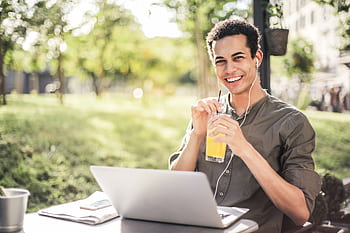 Cheerful man with laptop and juice relaxing outdoors. Ideal for lifestyle and lance themes. HD wallpaper
