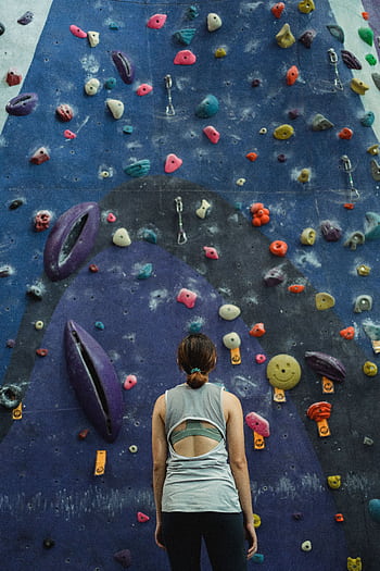 Focused woman in activewear facing an indoor climbing wall, preparing for ascent. HD phone wallpaper