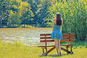 Woman enjoying a peaceful moment by a lake, embracing nature in summer. HD wallpaper