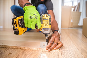 Man using a power drill for home improvement on a wooden floor with precision. HD wallpaper