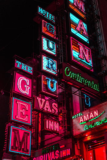 Dynamic neon signs illuminate the night, advertising city hotels with vivid colors. HD phone wallpaper