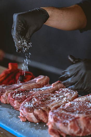 A chef seasons raw steaks with sea salt, perfecting the preparation process. HD phone wallpaper