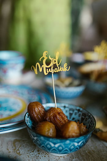 Charming Eid Mubarak scene with traditional sweets in a ceramic bowl, perfect for festive occasions. HD phone wallpaper