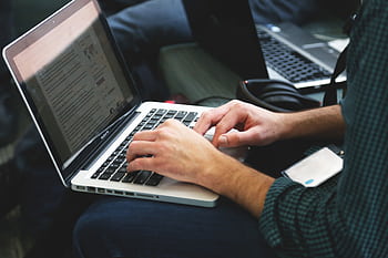 A programmer typing on a laptop in an indoor setting, showcasing technology in use. HD wallpaper